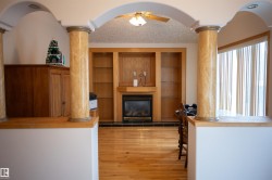 Hardwood flooring, arched entryways, integrated fireplace, built-in shelving, and large windows with vertical blinds - 