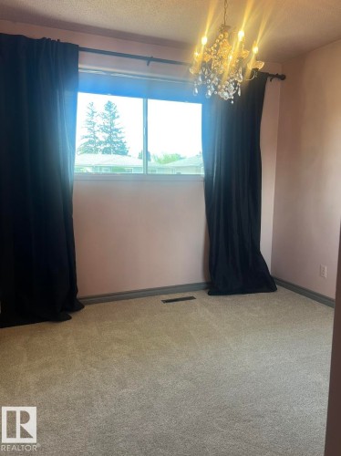 Plush carpeting, a large window, and a decorative chandelier - 15003 81 Street Nw, Edmonton, AB 
