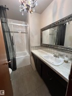 Vanity with an integrated sink, decorative framed mirror, and a wall-mounted chandelier - 