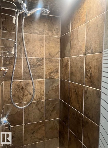 Tiled shower surround with a handheld shower head, a fixed shower head, and a chrome-finish shower valve - 15003 81 Street Nw, Edmonton, AB 