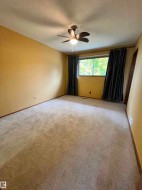 Wall-mounted light fixture with fan, window with dark blinds, and neutral-toned carpeting - 