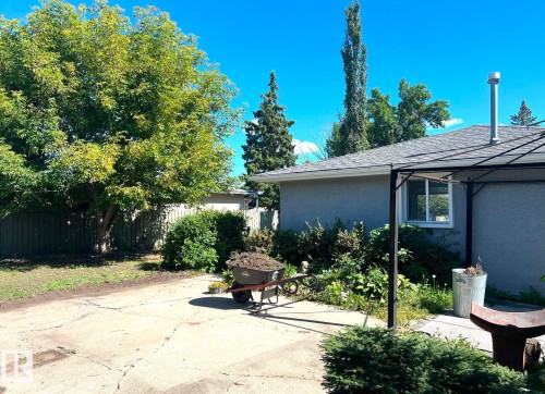 Exterior featuring stucco siding, shingle roofing, and a prominent window with white trim - 15003 81 Street Nw, Edmonton, AB 