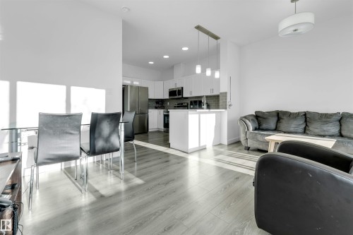 Open-concept living area with light wood-finish flooring, white walls, and recessed lighting - #62 2710 66 St Sw, Edmonton, AB 