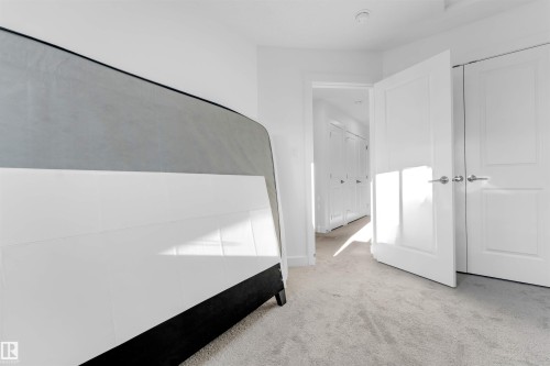 Light-toned carpeting, white interior doors with contemporary hardware, and a bright white paint scheme - #62 2710 66 St Sw, Edmonton, AB 
