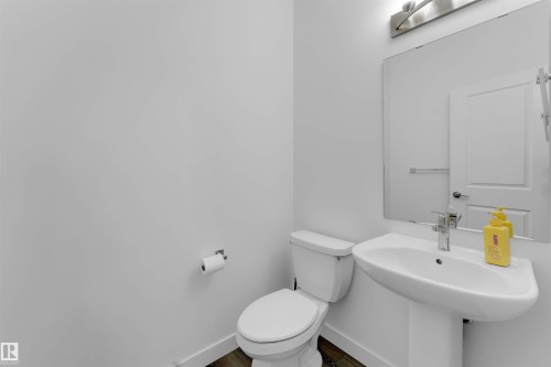 Pedestal sink with polished chrome faucet, rectangular mirror, and wood-finish flooring - #62 2710 66 St Sw, Edmonton, AB 