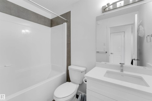 White single vanity with integrated sink, chrome faucet, and expansive mirror - #62 2710 66 St Sw, Edmonton, AB 