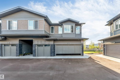 Multiple garages with overhead doors, stone accents, and siding exterior - #62 2710 66 St Sw, Edmonton, AB 