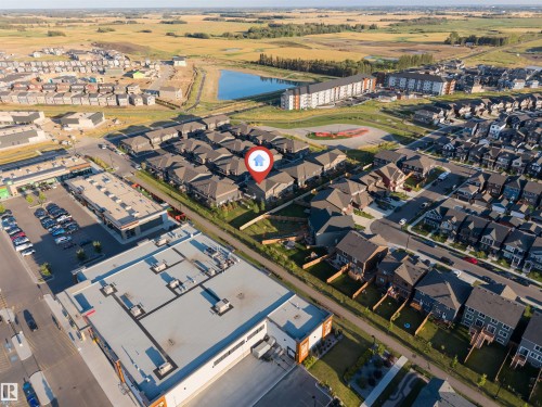 Aerial overview of the neighborhood featuring residential properties, commercial establishments, and a nearby pond - #62 2710 66 St Sw, Edmonton, AB 