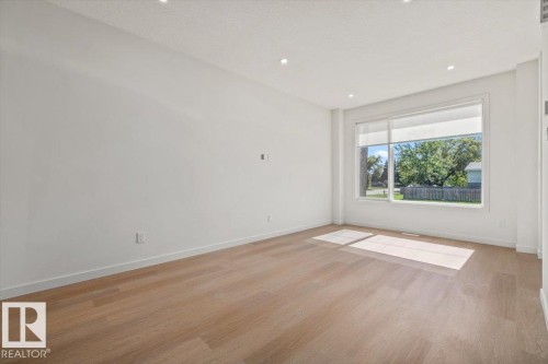 Recessed ceiling lighting, a large window, wood-finish flooring, and white walls - 15020 90 Avenue Northwest, Edmonton, AB 