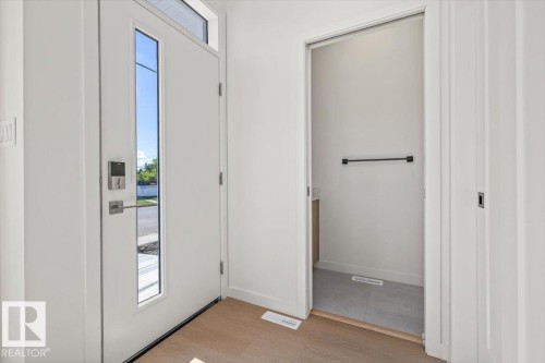 Entryway with wood-finish flooring and a white front door featuring a vertical window panel and transom window - 15020 90 Avenue Northwest, Edmonton, AB 