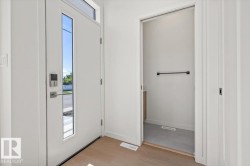 Entryway with wood-finish flooring and a white front door featuring a vertical window panel and transom window - 