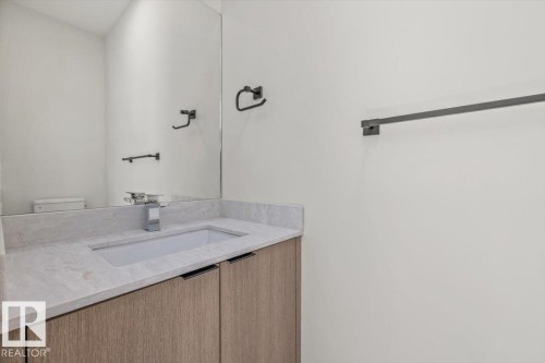 Built-in vanity with light wood-finish cabinetry, integrated sink, and stone countertop - 15020 90 Avenue Northwest, Edmonton, AB 