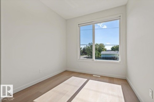 Expansive window providing natural illumination, wood-finish flooring, and white painted walls - 15020 90 Avenue Northwest, Edmonton, AB 