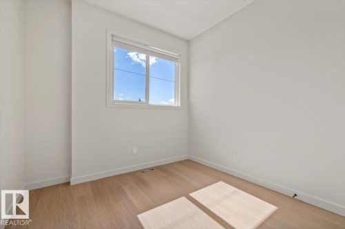 Neutral wall paint, wood-finish flooring, and a large window - 15020 90 Avenue Northwest, Edmonton, AB 