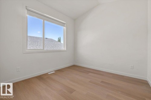 Light wood-finish flooring and white walls with a window featuring a roller shade - 15020 90 Avenue Northwest, Edmonton, AB 