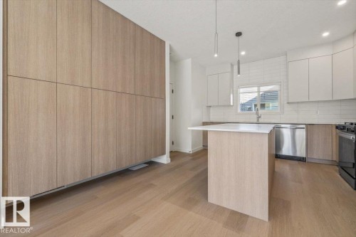 Kitchen featuring wood-finish flooring, a central island with white countertop, subway tile backsplash, stainless steel dishwasher, and contemporary pendant lighting - 15020 90 Avenue Northwest, Edmonton, AB 