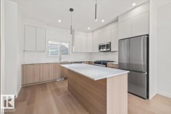 Kitchen featuring a central island, wood-finish flooring, white subway tile backsplash, and stainless steel appliances - 