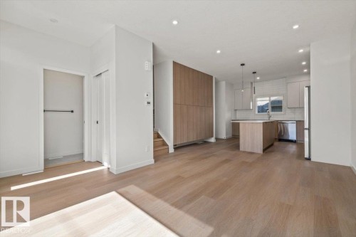 Wide plank wood-finish flooring, recessed lighting, and a modern kitchen featuring an island with pendant lighting and stainless steel appliances - 15020 90 Avenue Northwest, Edmonton, AB 