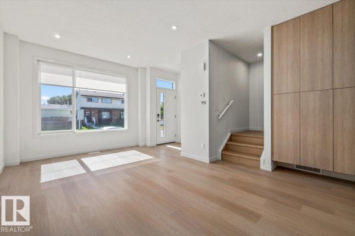 Recessed ceiling lighting, wood-finish flooring, a large window with roller shades, and built-in cabinetry with light wood-finish panels - 15020 90 Avenue Northwest, Edmonton, AB 