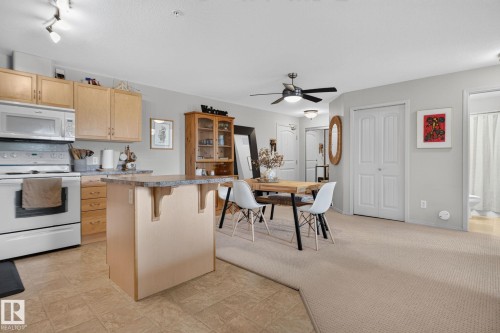 Open-concept living space featuring a kitchen with light wood cabinetry, white appliances, and a tiled floor - #335 2096 Blackmud Creek Dr Sw, Edmonton, AB - Indoor Photo Showing Kitchen