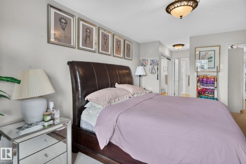 Bedroom featuring a dark wood sleigh bed, mirrored nightstand, and a built-in closet with sliding doors - #335 2096 Blackmud Creek Dr Sw, Edmonton, AB - Indoor Photo Showing Bedroom