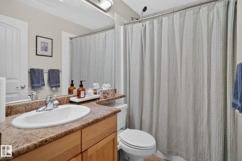 Bathroom featuring a built-in wood-finish vanity with an integrated sink and laminate countertop - #335 2096 Blackmud Creek Dr Sw, Edmonton, AB - Indoor Photo Showing Bathroom