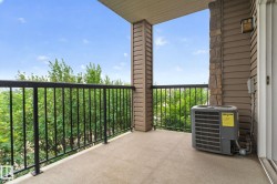 Private balcony featuring concrete flooring, black metal railings, and a stone veneer column - 