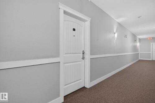 Entry door with vertical paneling and white trim - #335 2096 Blackmud Creek Dr Sw, Edmonton, AB - Indoor Photo Showing Other Room