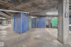 Concrete parking garage with exposed piping, fluorescent lighting, and designated storage units - 
