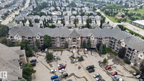 Multi-story residential building featuring balconies, a prominent main entrance, and a paved parking area - #335 2096 Blackmud Creek Dr Sw, Edmonton, AB -  With View