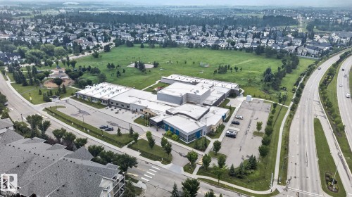 Aerial perspective showcasing a sprawling suburban neighborhood with extensive green spaces and established residential properties - #335 2096 Blackmud Creek Dr Sw, Edmonton, AB - Outdoor With View