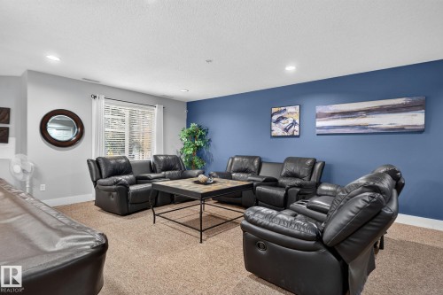 Carpeted living area featuring recessed lighting, a window with blinds and curtains, and a vibrant accent wall - #335 2096 Blackmud Creek Dr Sw, Edmonton, AB - Indoor Photo Showing Living Room