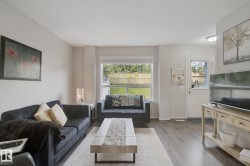 Hardwood-finish flooring, light neutral wall tones, rear yard access, and a large window with natural light - 