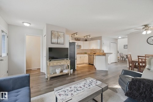 Wood-finish flooring throughout, white kitchen cabinetry, stainless steel appliances, and ceiling fan - 15618 141 Street Nw, Edmonton, AB 
