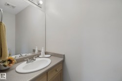 Vanity with an integrated oval sink, chrome faucet, and expansive wall mirror - 
