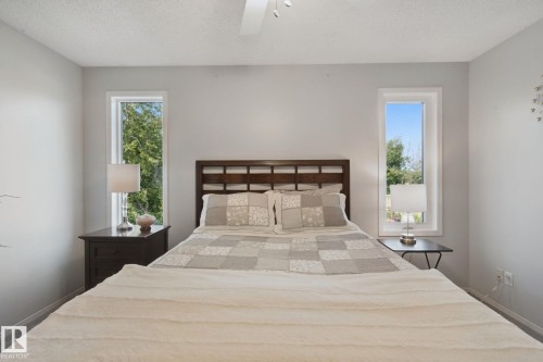 White walls frame a dark wood headboard, flanked by two vertical windows - 15618 141 Street Nw, Edmonton, AB 