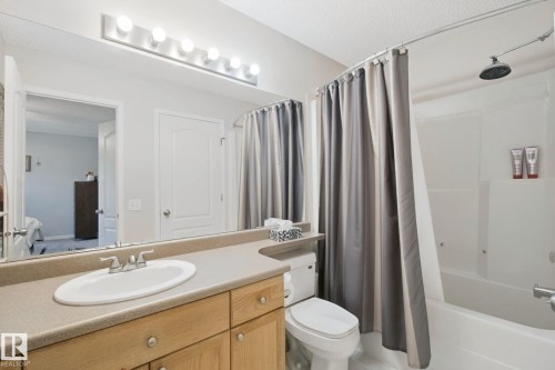 Spa-inspired bathroom featuring a wood-finish vanity with dual storage drawers, white porcelain sink, and quartz countertop - 15618 141 Street Nw, Edmonton, AB 