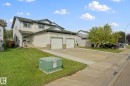 Two-story residence featuring light-colored siding, a two-car garage with white doors, and a concrete driveway - 15618 141 Street Nw, Edmonton, AB 