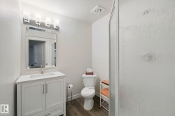 White vanity with brushed nickel hardware, a rectangular undermount sink, and a white countertop - 