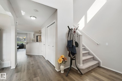 Wood-finish flooring, two bi-fold closet doors, staircase with carpeted treads, and a breakfast bar - 15618 141 Street Nw, Edmonton, AB 