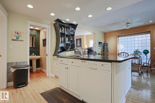 Kitchen island with dark countertop, white cabinetry, and integrated dishwasher - 10814 125 Street Nw, Edmonton, AB 