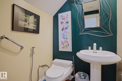 Pedestal sink with white basin, chrome faucet, and decorative mirror - 10814 125 Street Nw, Edmonton, AB 