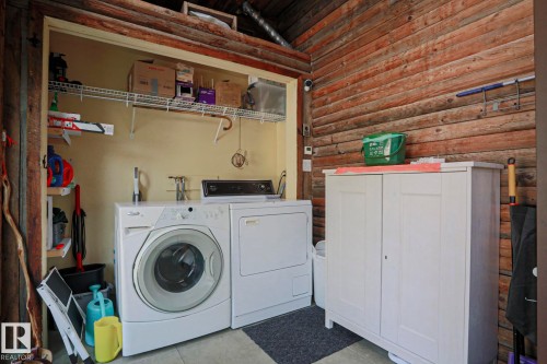 Laundry area featuring a side-by-side washer and dryer, wire shelving, and wood-paneled walls - 10814 125 Street Nw, Edmonton, AB 