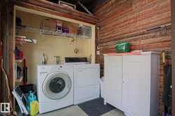 Laundry area featuring a side-by-side washer and dryer, wire shelving, and wood-paneled walls - 