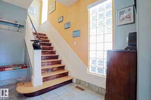 Staircase with wood-finish treads, white risers, and a prominent newel post - 10814 125 Street Nw, Edmonton, AB 