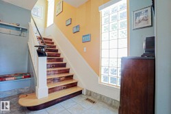 Staircase with wood-finish treads, white risers, and a prominent newel post - 