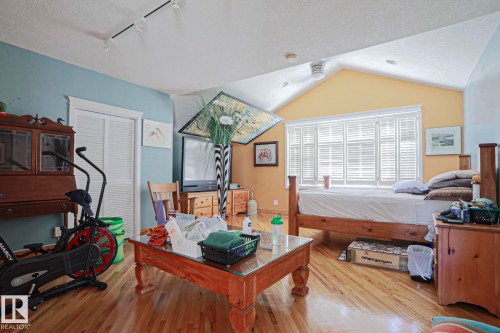 Wood-finish flooring, vaulted ceiling, track lighting, ceiling fan, and window with plantation shutters - 10814 125 Street Nw, Edmonton, AB 