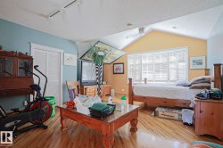 Wood-finish flooring, vaulted ceiling, track lighting, ceiling fan, and window with plantation shutters - 