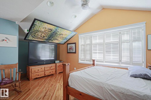 Vaulted ceiling with recessed lighting, wood-finish flooring, white window shutters, ceiling fan, and a built-in entertainment unit - 10814 125 Street Nw, Edmonton, AB 