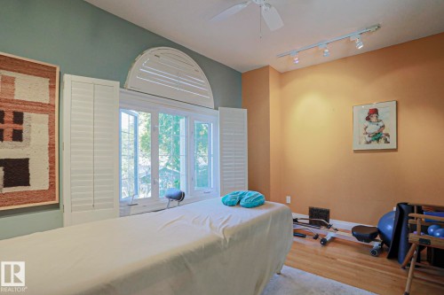 Hardwood flooring, multi-pane window with arched transom, white plantation shutters, ceiling fan, and track lighting - 10814 125 Street Nw, Edmonton, AB 